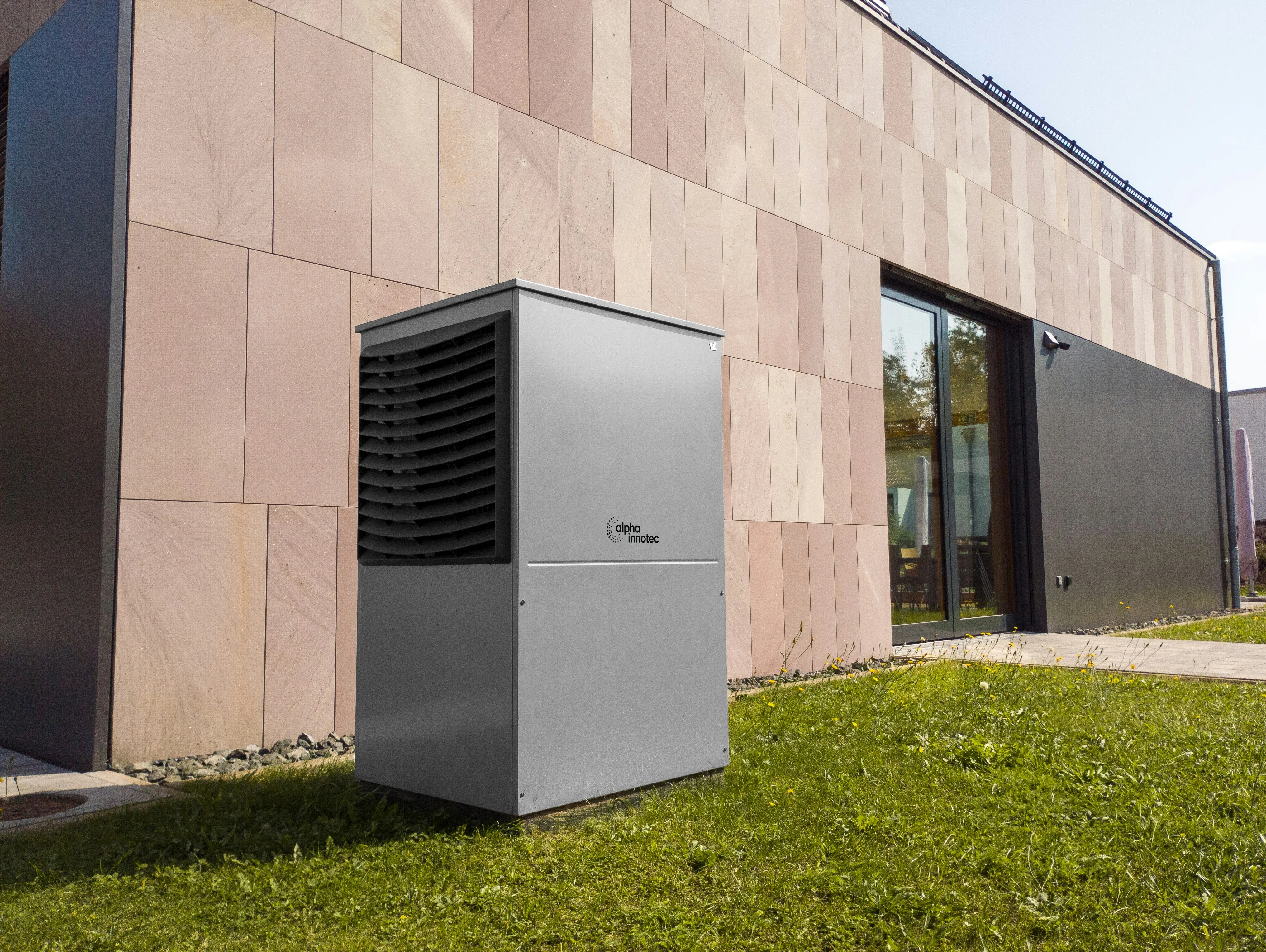 Air source heat pump outdoor unit set against an exterior wall — the system draws heat from outside air