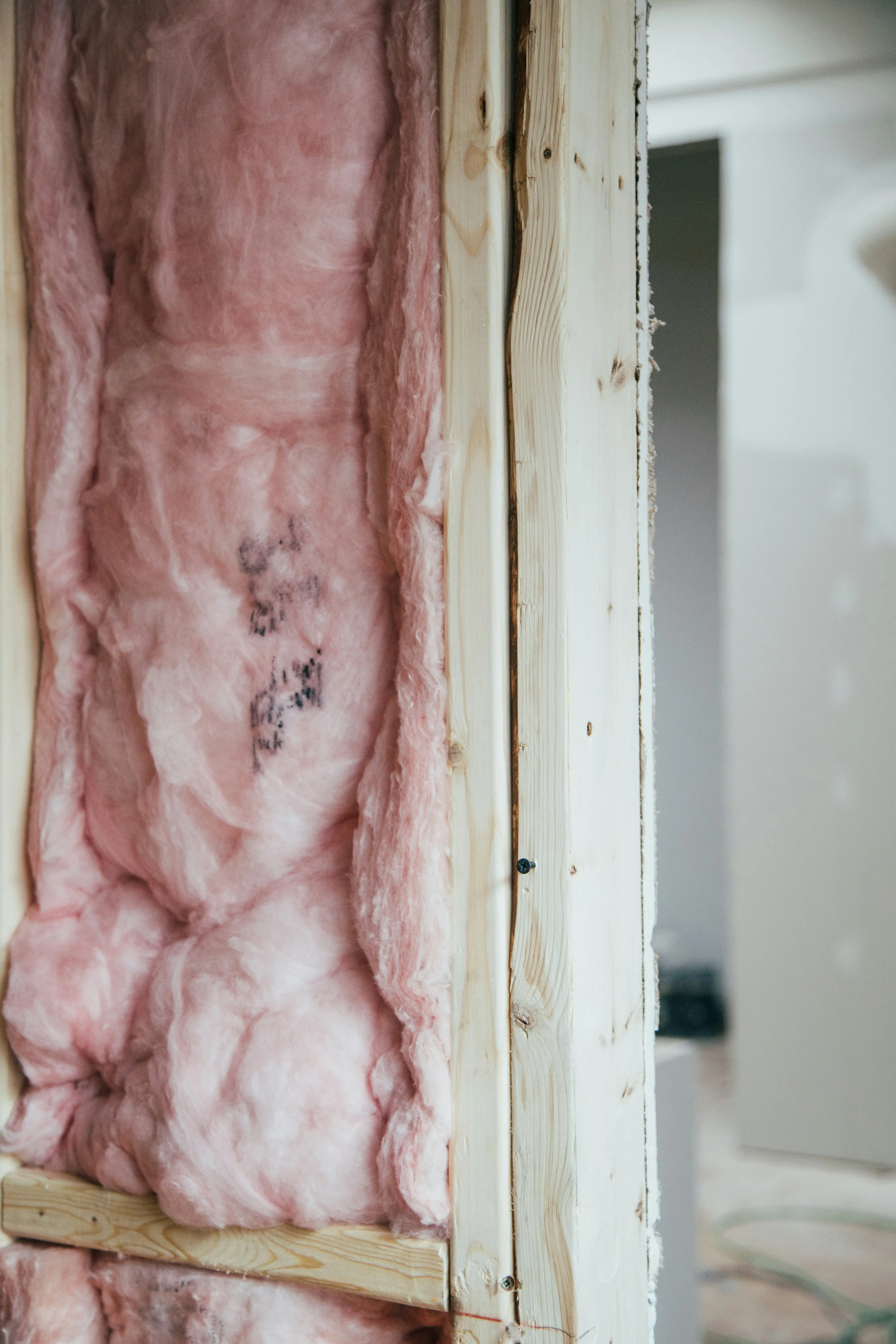 Pink mineral-wool insulation installed between timber wall studs — a fabric-first measure to consider before fitting a heat pump